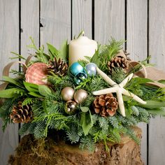 a christmas arrangement with pine cones, starfish and other holiday decorations on a tree stump