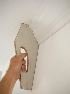 a person holding a wooden object in their hand and pointing it at something on the wall