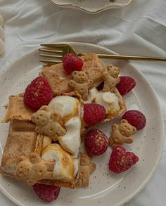 a white plate topped with waffles and raspberries next to a fork