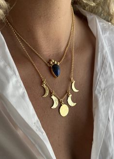 a woman wearing three different necklaces with moon and heart charms on her neck,