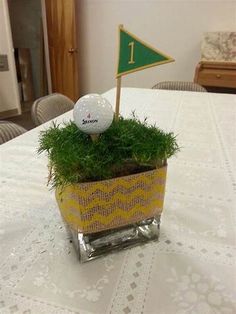 a golf ball sitting on top of a table next to a planter filled with grass