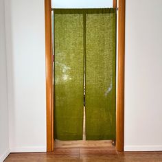 an open door with green fabric covering the doors and wood trimmings on it