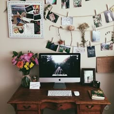 a desktop computer sitting on top of a wooden desk next to a wall covered in pictures