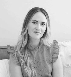 a black and white photo of a woman sitting on a couch looking at the camera