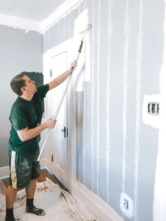 a man in green shirt painting walls with white paint