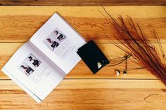 an open book sitting on top of a wooden floor next to dried flowers and a plant