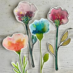 three watercolor flowers on a white wooden surface