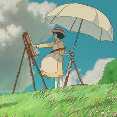 a woman standing on top of a lush green field next to an easel and umbrella