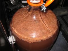 a large brown pot sitting on top of a stove next to a white and orange object