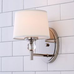 a wall light with a white shade on it's side against a white brick wall