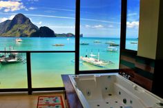 a large bath tub sitting under a window next to a bathroom with a view of the ocean