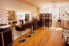 a salon with chairs, mirrors and lights on the wall in front of it's windows