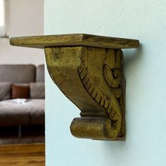 a wooden shelf with an elephant head on the wall next to a couch and coffee table