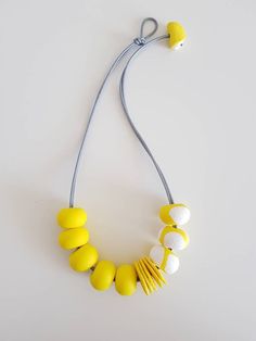 a yellow and white necklace on a gray string