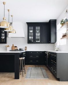 a kitchen with black cabinets and white counter tops is seen in this image, there are stools at the center of the room