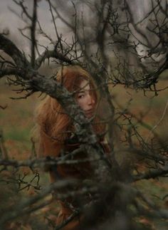 a woman is hiding behind some branches