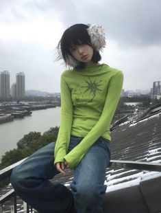 a young woman sitting on top of a metal rail next to a body of water