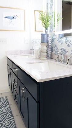 a bathroom with two sinks and a large mirror on the wall above it is decorated in blue and white