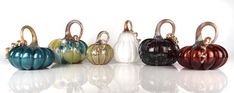 several different colored pumpkins sitting next to each other on a white surface with reflections