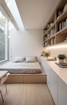 a bed sitting under a window next to a desk and bookshelf in a bedroom