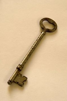 an old key is sitting on a white surface with a shadow from the keys behind it