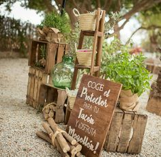 a sign that is sitting on the ground in front of some wooden crates and plants