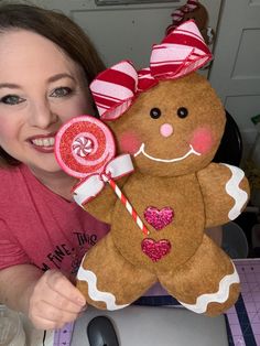 a woman holding up a giant ginger with a candy lollipop in her hand