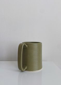 a green mug sitting on top of a white table