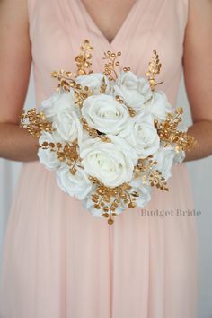 a bridal holding a bouquet of white roses and gold leaves in her hands with the bridesmaid's dress behind her