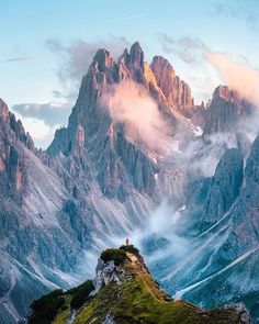 a person standing on top of a mountain looking at the clouds in the sky above