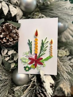 a christmas card with candles on it next to a pine cone and fir tree branch