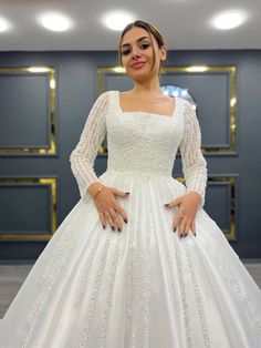 a woman in a white wedding dress posing for the camera with her hands on her hips