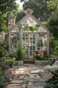 an old greenhouse in the middle of a garden with lots of flowers and greenery