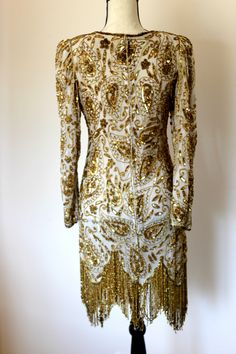 "Beautiful Gunit Flapper Dress with Gold beads and sequins throughout. Excellent condition! Long flowy gold beaded fringe. This one is a true head turner!! Zipper in the back Measuring: 36\" long 34\" bust 28\" waist 34\" hip 23\" sleeve Beautiful! in every way!! Pet free/ smoke free Enjoy!" Gold Party Dress With Rhinestone Fringe, Elegant Gold Dress With Rhinestone Fringe, Gold Evening Dress With Rhinestone Fringe, Gold Rhinestone Fringe Evening Dress, Gold Sequin Evening Dress For Formal Occasions, Gold Sequin Dress For Formal Evening, Gold Sequin Formal Dress For Evening, Gold Embellished Sequin Dress For Party Season, Festive Gold Sequin Dress For Gala