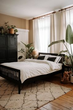 a bedroom with a bed, dresser and plants in it