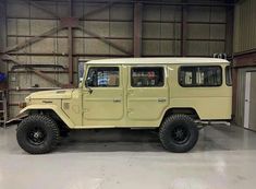 an old yellow jeep is parked in a garage