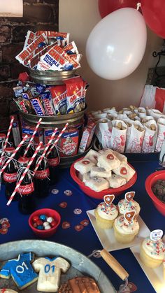 a table topped with lots of cupcakes and cookies next to red white and blue balloons