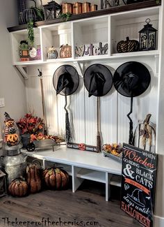 a white shelf filled with lots of hats and pumpkins next to a sign that says halloween