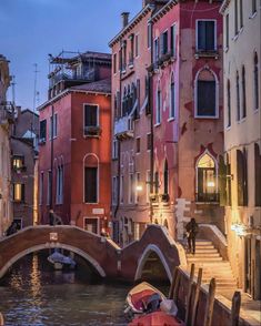 a small bridge over a canal with boats in the water and buildings on either side