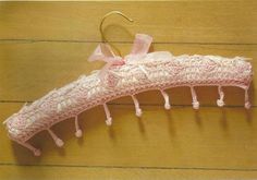 a pink crocheted umbrella is hanging on a wooden floor with a hook in it