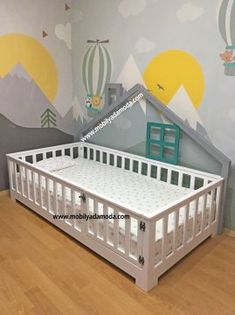 a baby crib in front of a wall with hot air balloons painted on it