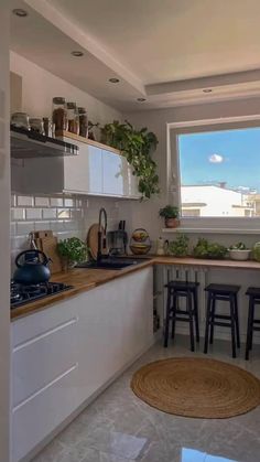 a kitchen with lots of counter space and plants on the window sill over the stove