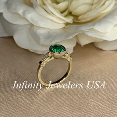 "The ring pictured is lab created emerald with moissanite accents #7056 -Approximate total carat weight: 1.26ctw diamond equivalent -Center Stone Size: 7mm - approx. 1.20ct diamond equivalent -Center Stone Shape: round -Gem Type: lab created emerald -Stone Clarity: VS2 -Stone Color: green -Moh's Scale: 8.5 hardness -Accent Stones: 2 rounds - approx. 0.06ctw. diamond equivalent -Gem Type: moissanite -Stone Clarity: VS2 -Stone Color: FG -Moh's Scale: 9.25 hardness -Metal Type and Purity: 14k white Emerald Ring With Diamond Center Stone For May Birthstone, May Birthstone Emerald Ring With Diamond Center Stone, Emerald Diamond Ring For May Birthstone With Center Stone, Diamond May Birthstone Ring With Center Stone, Diamond Birthstone Ring With Center Stone For May, Classic Moissanite Emerald Ring For May Birthstone, Moissanite Emerald Ring For May Birthstone, Classic Emerald Ring With Tsavorite Accent Stones, Promise Emerald Ring With Diamond Bezel Setting