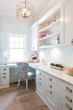 a kitchen with white cabinets and gold hardware on the countertop, along with a blue chair