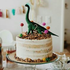 there is a cake decorated with dinosaurs on the top and decorations in the bottom tier