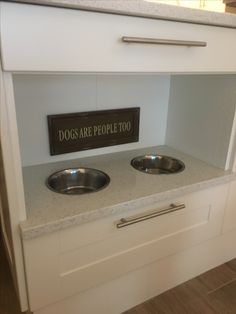 two stainless steel bowls are on the counter in front of a sign that says dogs are people too