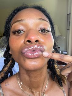 a woman with dreadlocks making a funny face while holding her finger up to her mouth