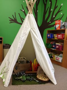 a teepee tent in the corner of a room with green walls and trees painted on it