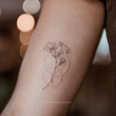 a small flower tattoo on the left arm is shown in black ink, and has dots all over it