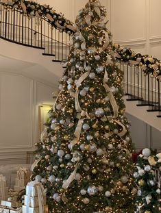 a decorated christmas tree in the middle of a room with white and silver decorations on it